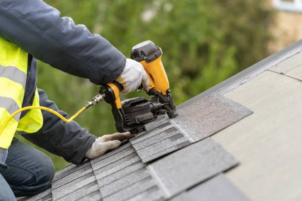 Worker installing asphalt shingles using nail gun, ensuring roof durability. -tile roof installation