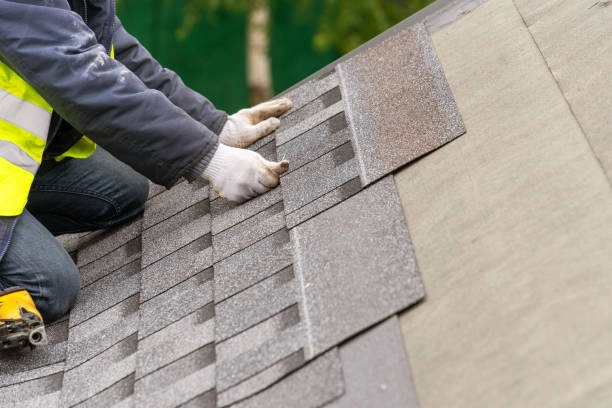 Worker aligning asphalt shingles on roof, ensuring proper installation accuracy. -tile roofing contractors