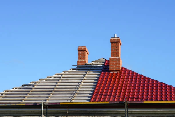 Half-completed red tile roof with brick chimneys against blue sky. -tile roof replacement