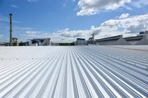 Industrial metal roofing with a bright sky and factory buildings. -commercial roofing contractors