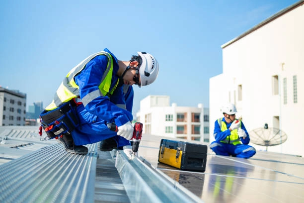 Construction workers installing metal roofing panels on a commercial building. -commercial roofing contractors