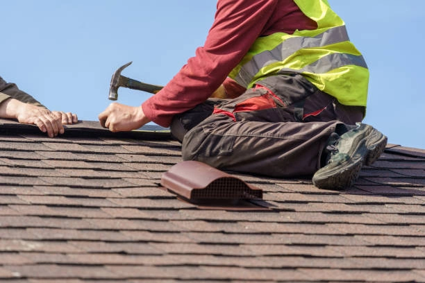 Worker installing asphalt shingles on a roof using a hammer. -commercial roof contractors