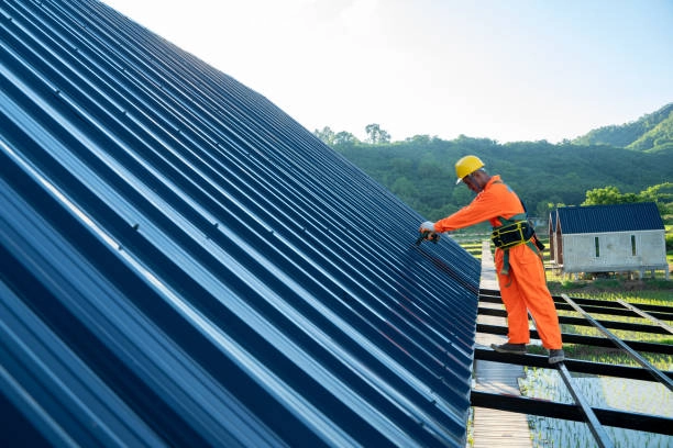 Worker installing blue metal roofing on a steep roof structure. -commercial roof contractors