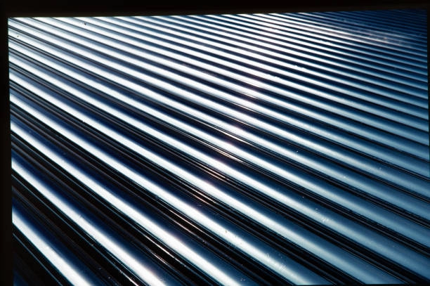 Shiny corrugated metal roof reflecting sunlight with parallel ridged lines. -commercial roofer contractors