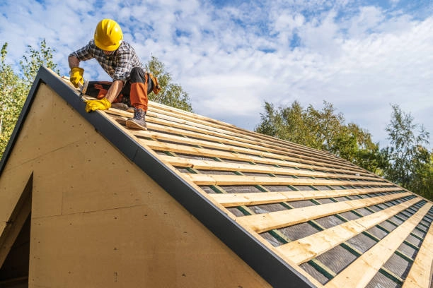 Worker in safety gear installing roof edge on wooden structure. -commercial roofer