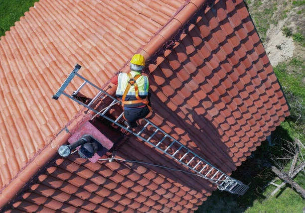 Worker in safety gear repairing red tile roof using ladder. -roof repair phoenix