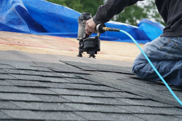 Worker installing asphalt shingles using a pneumatic nail gun.- roof repair phoenix