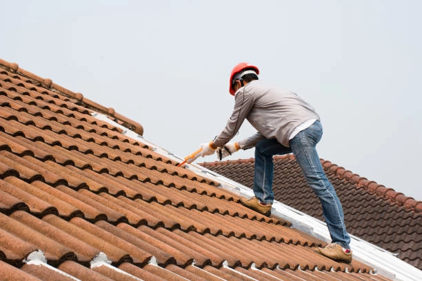 Worker in safety gear sealing joints on a brown tile roof. -roof repair phoenix